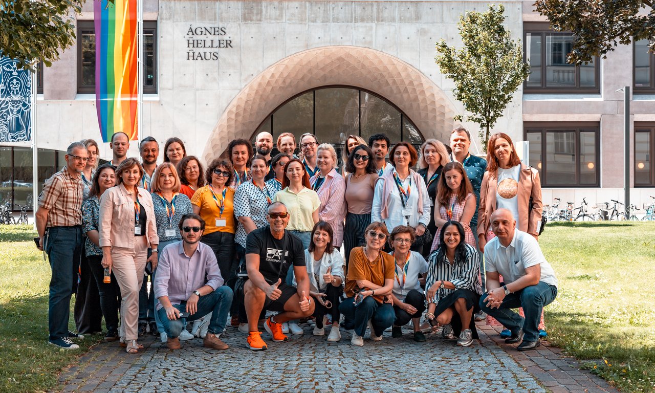 Gruppenfoto bei schönem Wetter im Freien, im Hintergrund ist das Ágnes-Heller-Haus zu sehen.