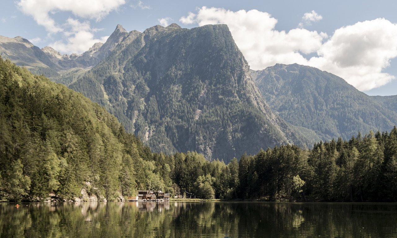 View of a lake surrounded by trees, with a large mountain range in the background.