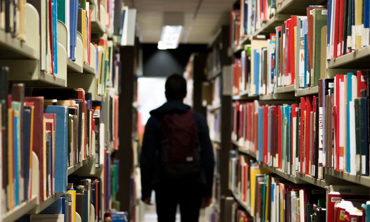 Mann im Schatten zwischen Bücherregalen
