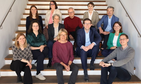 Mitglieder des Instituts für Praktische Theologie sitzen auf den Stufen einer Treppe.
