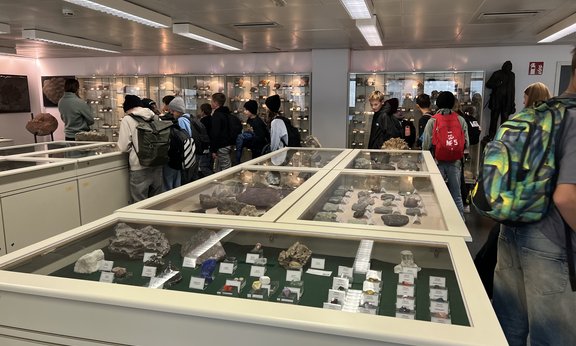 Schulklasse wird durch die Vitrinen der Schausammlung mit Fossilien, Mineralen und Gesteinen geführt