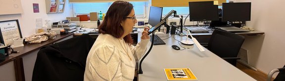 eine junge Frau nutzt die Handylesehilfe und schreibt gerade in ihrem Notizbuch