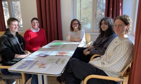 Zu sehen sind Teilnehmer:innen des Theotags. Sie sitzen an einem Tisch.