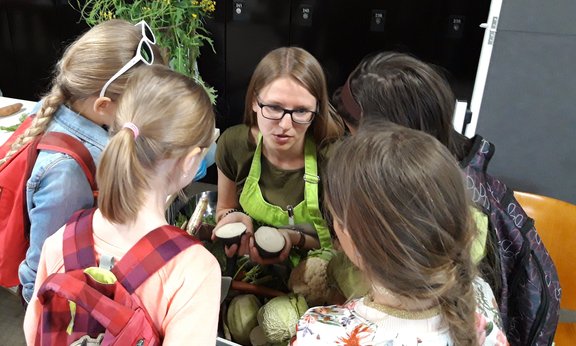 Lehrerin mit vier Kindern zeigt Gemüse
