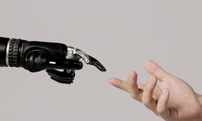 Symbolbild: Roboterhand und Menschenhand berühren einander fast mit ausgestreckten Zeigenfingern.