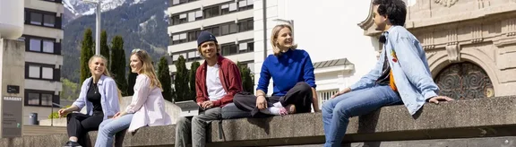 Studierende sitzen auf der Mauer vor der Universität Innsbruck