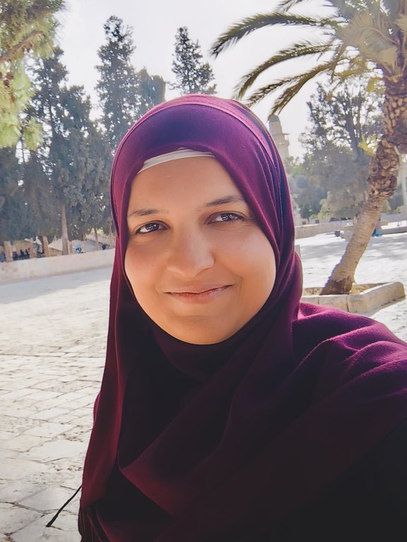 Meryam Ben Bouaicham Palmen im Hintergrund, braun-rotes Kopftuch, lächelt