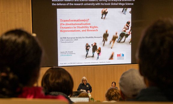 Blick in den Hörsaal Audimax mit sitzenden Menschen.