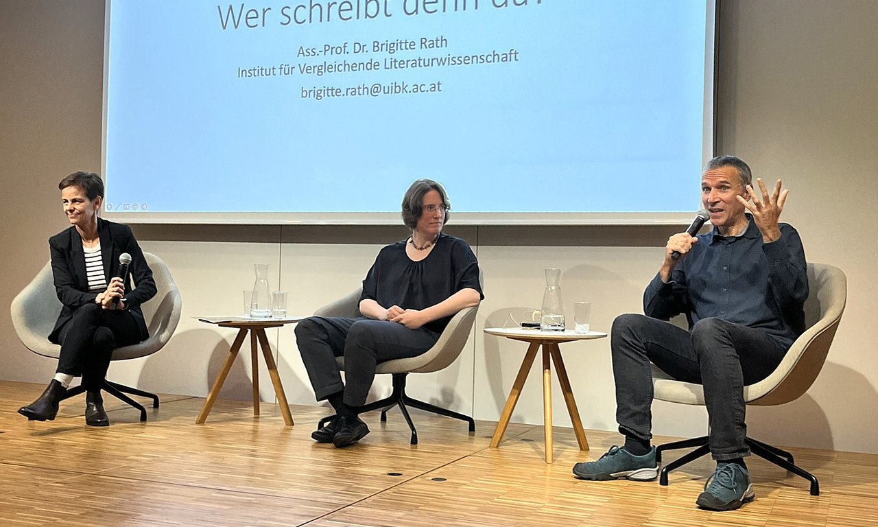 Drei Personen auf einem Podium.