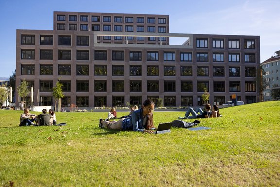 Studierende sitzen in der Wiese vor dem Ágnes-Heller-Haus