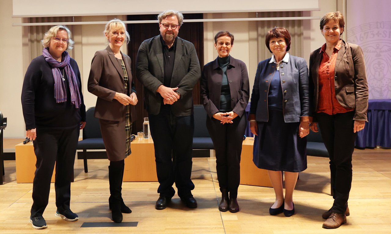 Gruppenbild von Vortragenden und Diskussionsteilnehmer:innen in der Aula