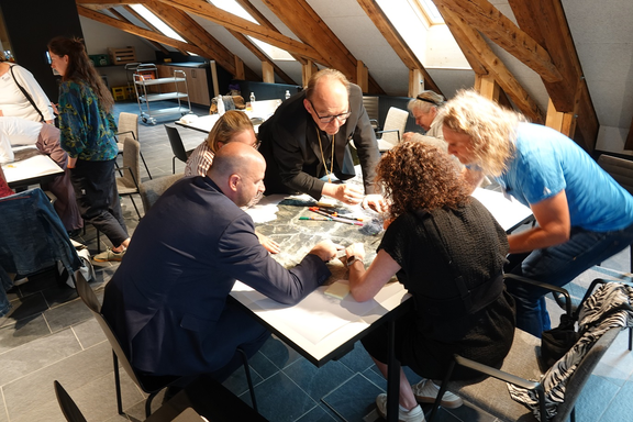 Workshop-Gruppe an einem Tisch über einer Landkarte