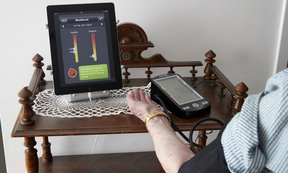 Eine ältere Frau misst ihren Blutdruck mithilfe eines modernen Tablets