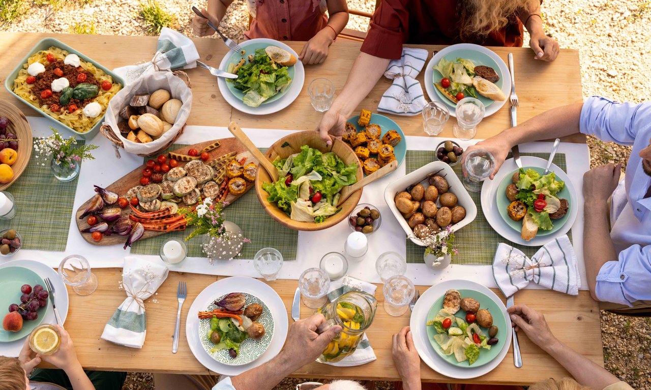 Vegetarisches Festessen von oben fotografiert, angeschnitten sind auch Personen zu sehen.
