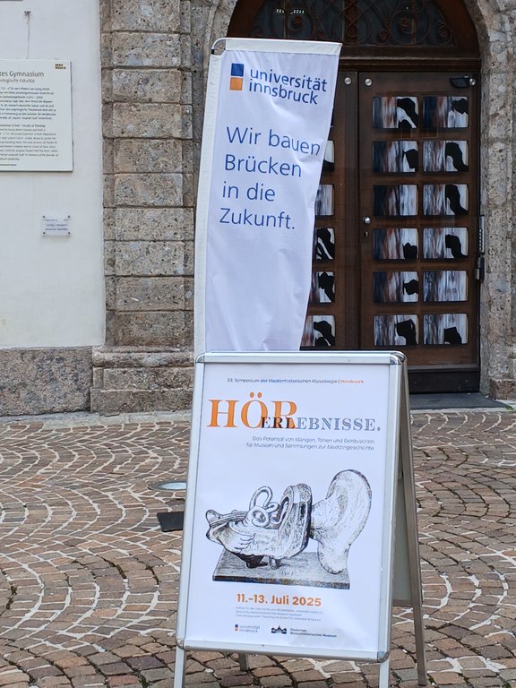 Foto von einem Aufsteller für das Symposium HörErlebnisse im Juli 2025