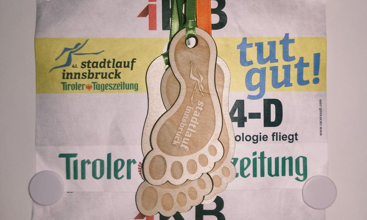 Zu sehen sind die Teilnahmeurkunde, es sind kleine Füße aus Holz zum Umhängen.