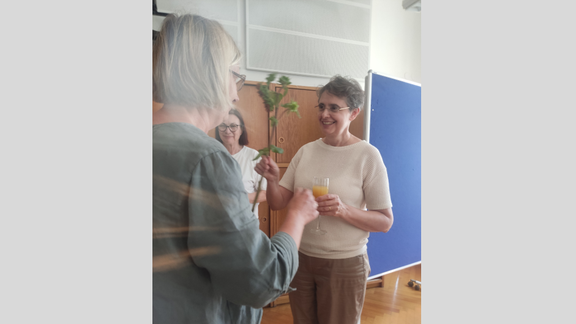 Zu sehen sind die Mitglieder des Instituts beim Sommerumtrunk. Es werden Blumen zum Geburtstag überreicht.