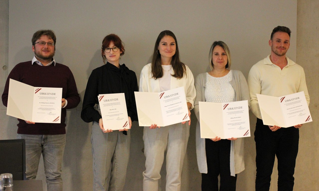 Gruppenfoto mit fünf Personen, alle fünf halten Urkunden.