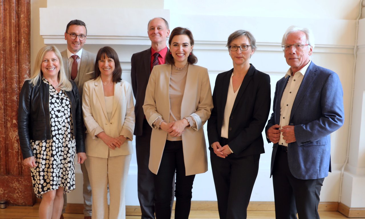 Vertreter:innen des IRKS mit Ministerin Alma Zadic in der Mitte auf einem Gruppenbild.