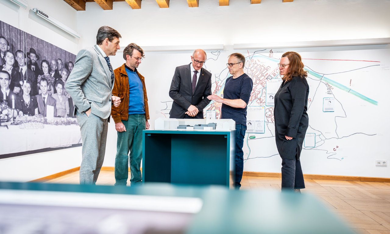 Fünf Personen stehen um einen Tisch und betrachten Ausstellungsgegenstände