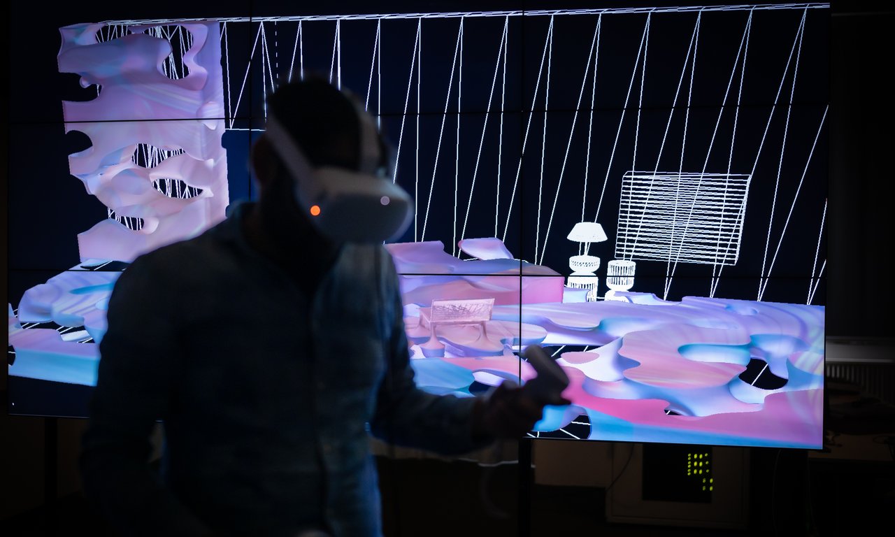 Mann mit VR-Brille vor Videowand