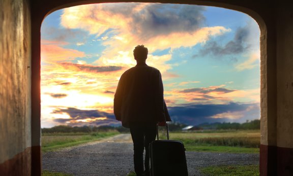 Reisender mit Koffer zieht in die Welt hinaus
