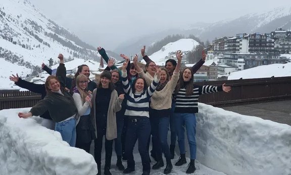 Gruppen von Leuten, die die Hände in die Höhe werfen, vor verschneiter Winterlandschaft