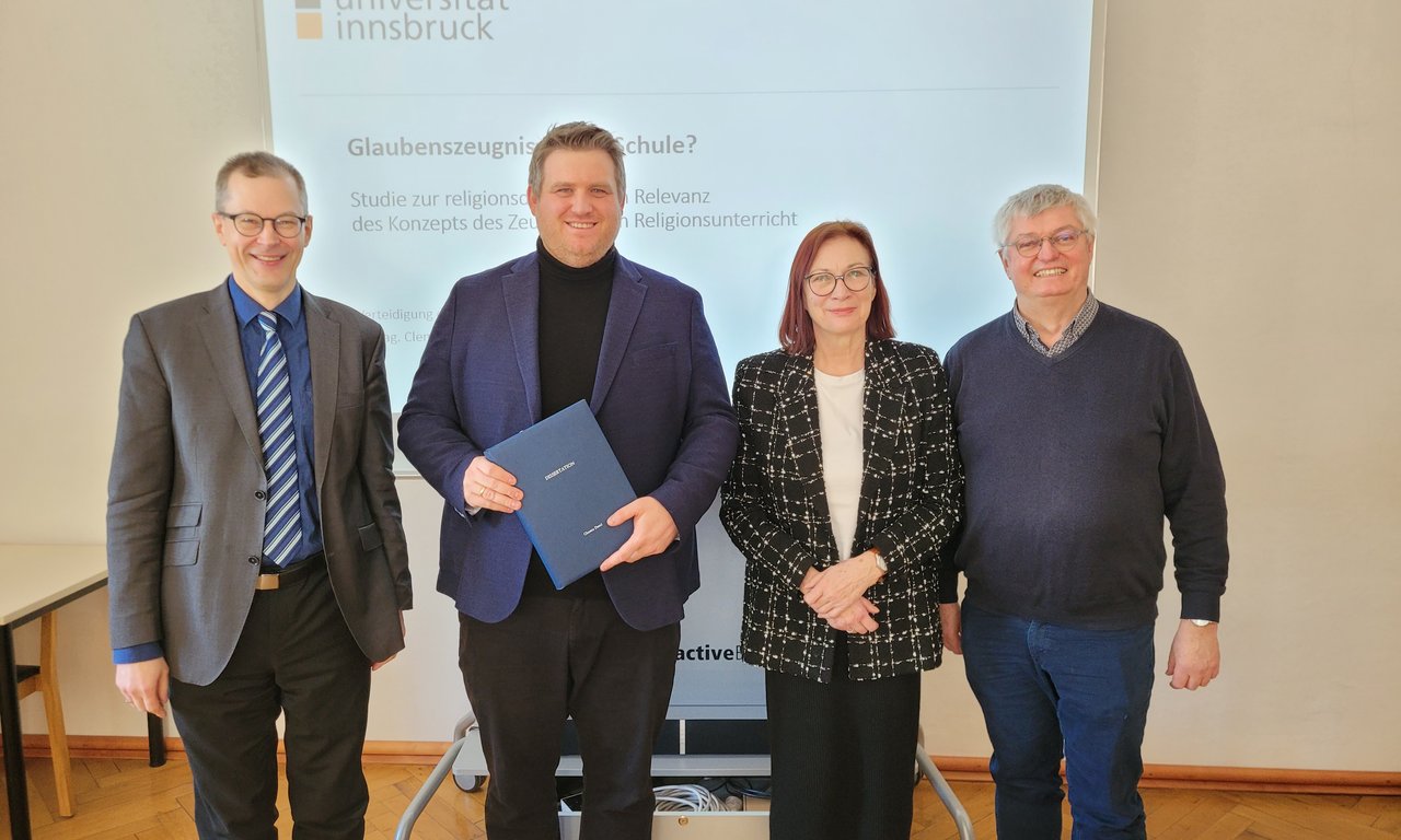Zu sehen sind Studiendekan Liborius Lumma, Clemens Danzl, Gutachterin Martina Kraml und Gutachter Hans Mendl. Sie stehen in einer Reihe. Clemens Danzl hält die Promotionsurkunde in den Händen.