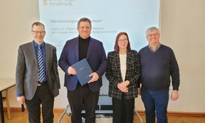 Zu sehen sind Studiendekan Liborius Lumma, Clemens Danzl, Gutachterin Martina Kraml und Gutachter Hans Mendl. Sie stehen in einer Reihe. Clemens Danzl hält die Promotionsurkunde in den Händen.