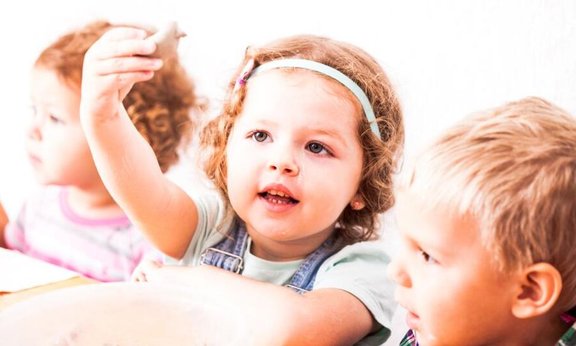 Drei Kinder an einem Tisch sitzend.