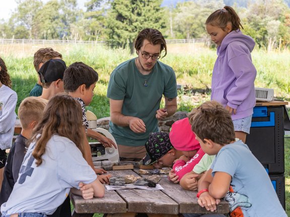 Workshopleiter und Kinder rund um einen Tisch