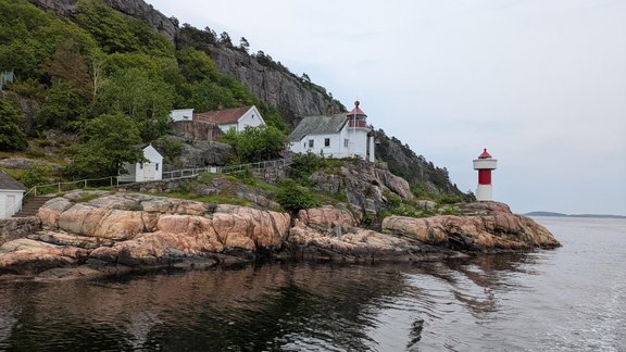 Zu sehen sind die norwegischen Fjorde, Küstenlandschaft und ein Leuchtturm.