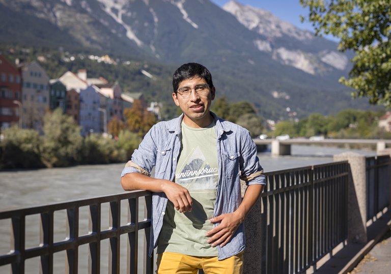 Porträt von Elwin Huaman vor dem Inn; im Hintergrund Berge