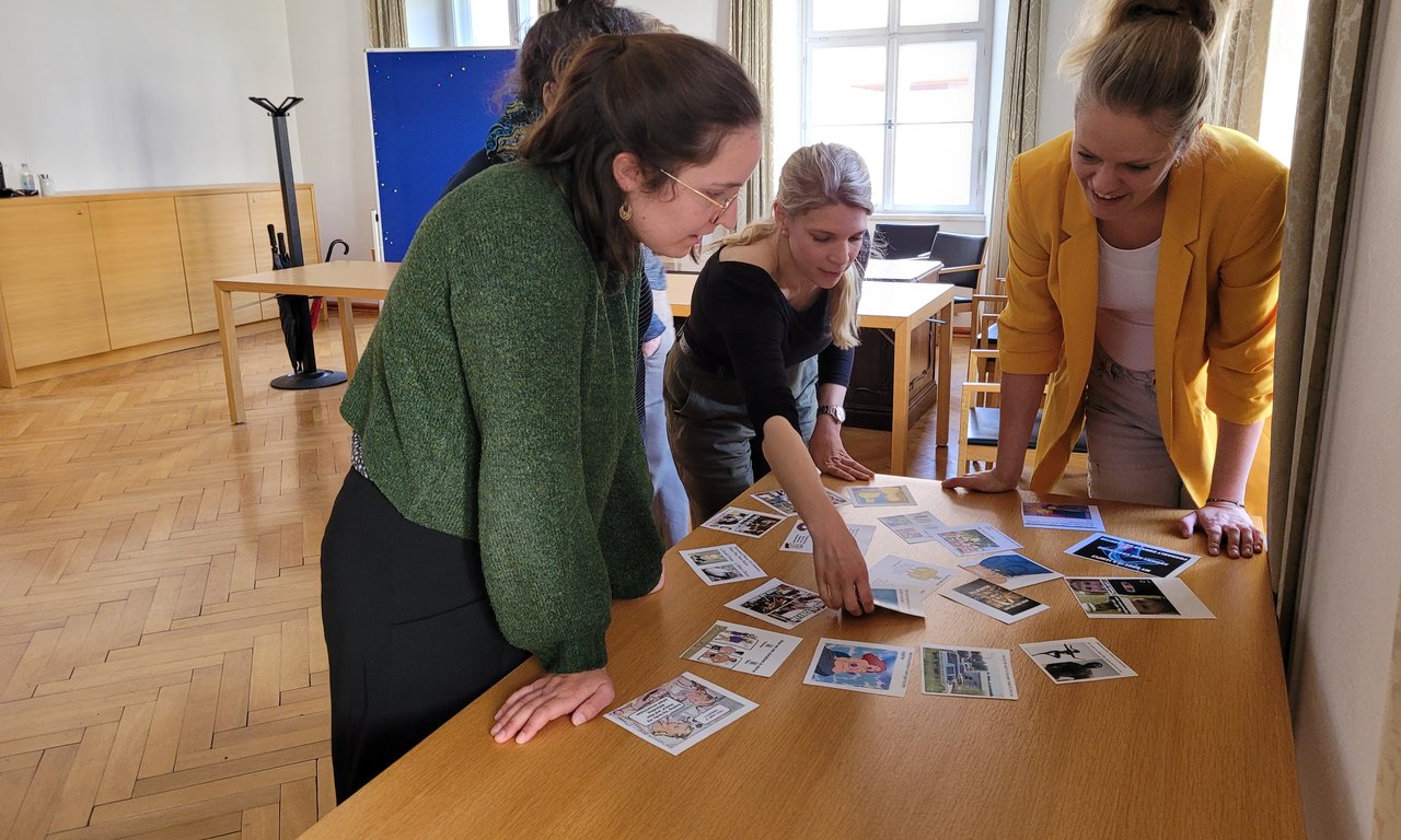 drei Personen um einen Tisch herum