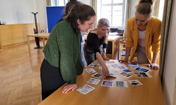 drei Personen um einen Tisch herum