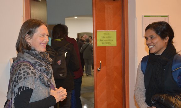 Eine Frau begrüßt eine junge Frau mit dunkler Hautfarbe