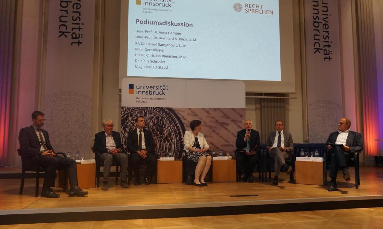 Die Teilnehmenden der Podiumsdiskussion während der Veranstaltung sitzen auf der Bühne in der Aula.