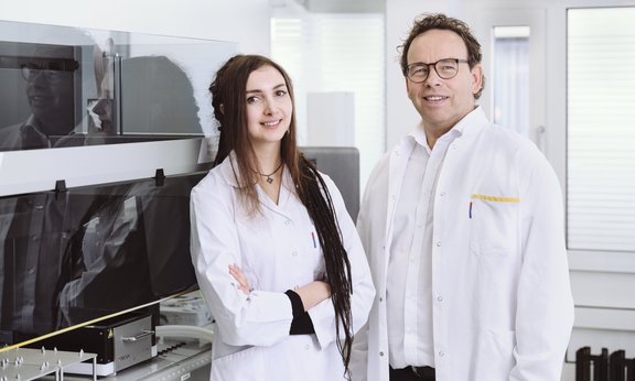 Portraitfoto von Martin Widschwendter und Chiara Herzog in weißen Laborkitteln in ihrem Labor