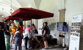 Interessierte Besucher:innen vor dem Info-Stand der Uni Innsbruck im Volkskunstmuseum.