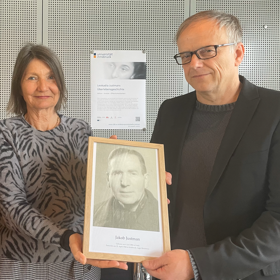 Die derzeitige Innsbrucker Stadträtin Ursula Schwarzl (links) hält mit Projektleiter Niko Hofinger (rechts) das Portrait von Jakob Justman in der Hand.