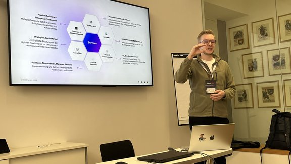 David Hauser gestikuliert, während er die Folie am Bildschirm hinter sich erklärt.