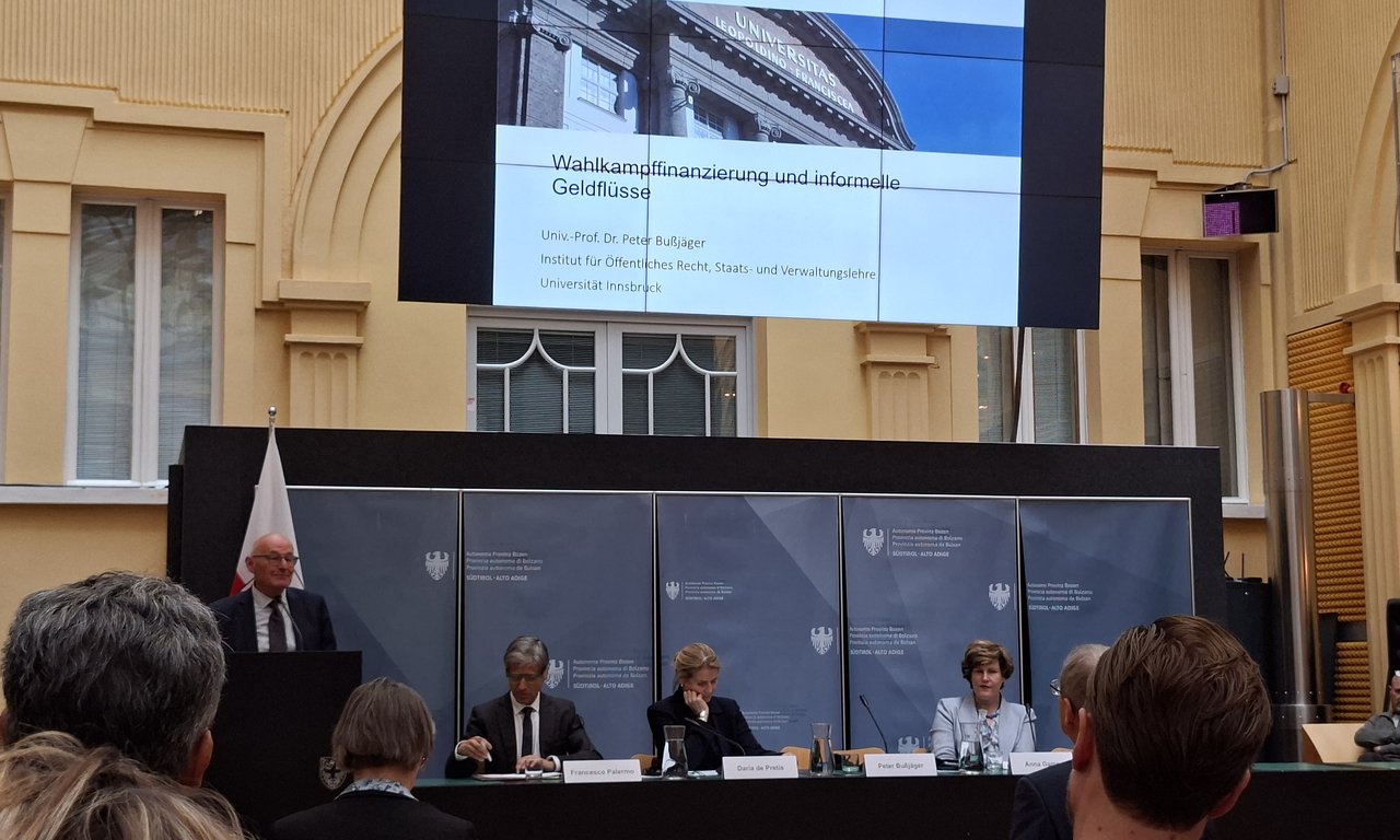 Mehrere Personen sitzen auf einem Podium