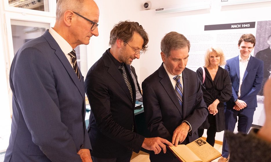 Ausstellungseröffnung Justman. V.l.n.r.: Landeshauptmann Anton Mattle, Dominik Markl SJ, Jeffrey Wisnicki, Rebecca Wisnicki und Brandon Wisnicki. Jeffrey Wisnicki präsentiert das von seiner Mutter Leokadia Justman 1945 in Innsbruck geschriebene Album bei der Eröffnung der Ausstellung am 27. Jänner 2025. Bild: Land Tirol/Die Fotografen