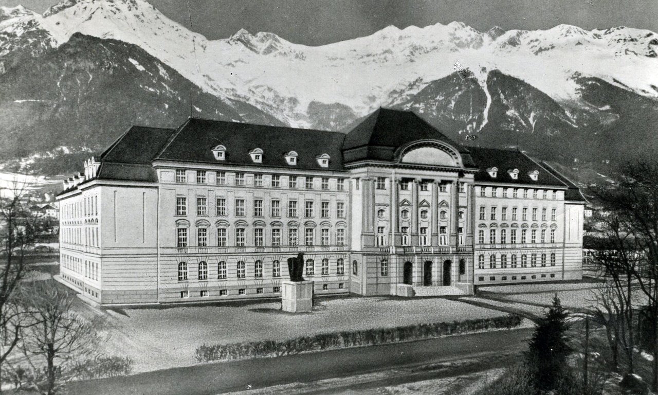 Historische Aufnahme des Hauptgebäudes der Universität mit der Nordkette im Hintergrund.