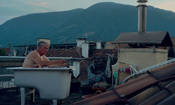 Matthias Schönweger in der Badewanne auf dem Hausdach bei der Arbeit
