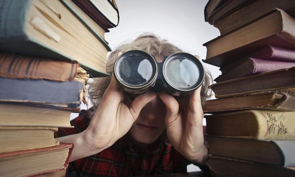 Anonyme Person Mit Fernglas, Die Durch Gestapelte Bücher Schaut