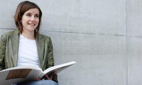 lächelnde Frau mit offenen Buch in der Buch