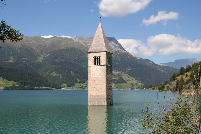 Foto von dem aus dem Wasser ragende Kirchturm von Alt-Graun im Reschenstausee (Foto: Adrian Michael 2011, Wikimedia Commons)
