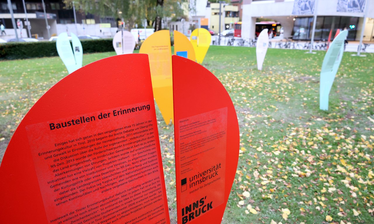 Eine rote Ausstellungstafel mit nicht lesbaren Text